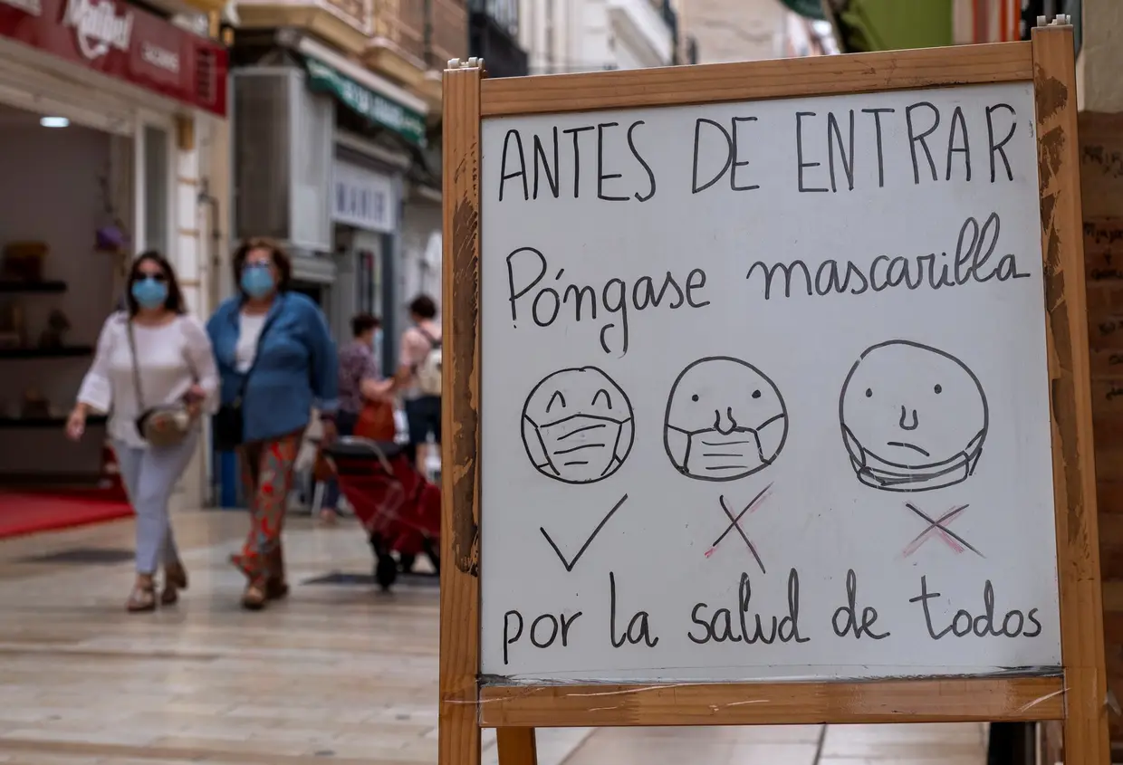 Um sinal que mostra às pessoas como devem usar a máscara para entrar numa loja, em Huelva, Espanha.