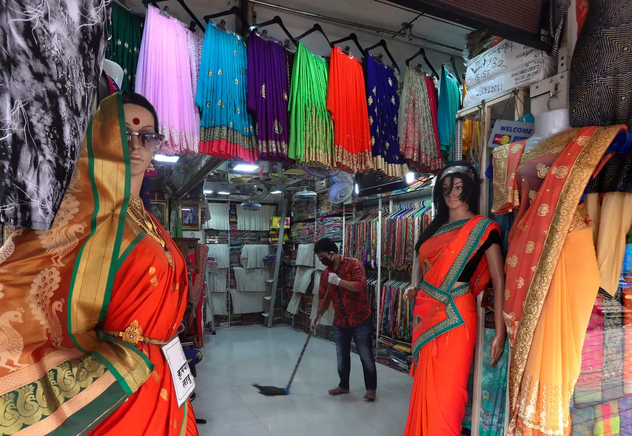 Comerciante a limpar a loja, em Mumbai, Índia.