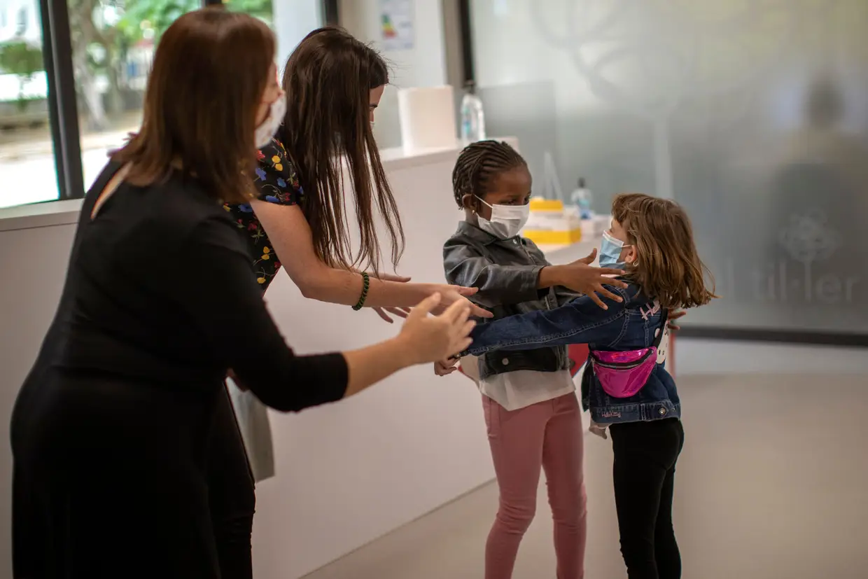 Duas professoras a tentar evitar um abraço entre duas colegas que regressaram à escola, em Barcelona, Espanha.
