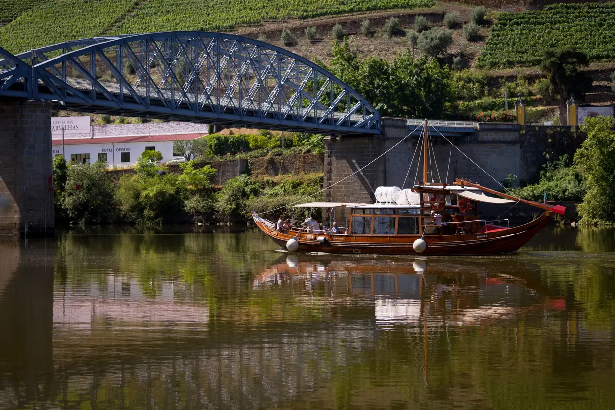 Um barco turístico do Douro a passar com turistas a bordo pela ponte do Pinhão, Vila Real.