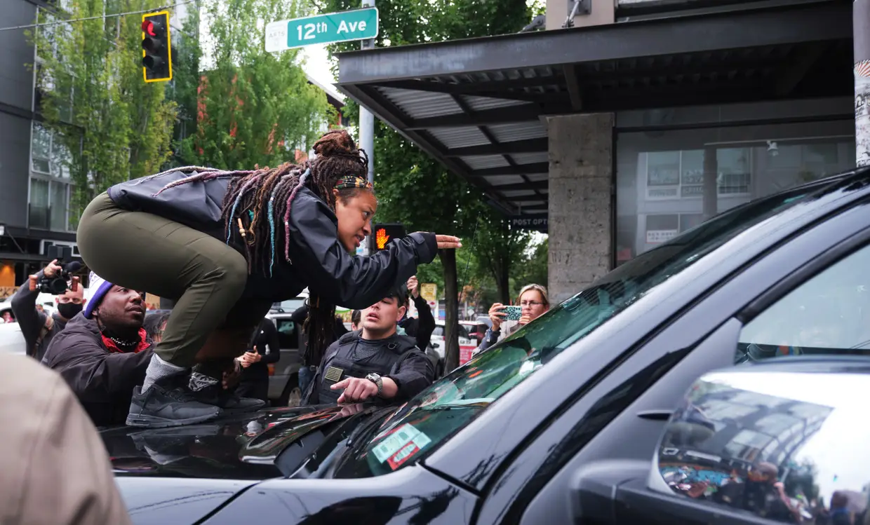 Uma manifestante do movimento "Black Lives Matter" em cima de uma carrinha durante um confronto com uma equipa de televisão da FOX News, em Seattle, Washington.