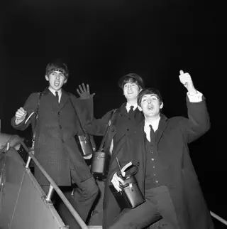 Três membros da banda britânica Os Beatles no aeroporto de Lontres. Da esquerda para a direita: George Harrison, John Lennon e Paul McCartney.