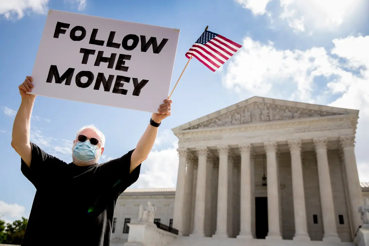Bill Christeson a segurar um cartaz onde se pode ler "Sigam o dinheiro" em frente ao Supremo Tribunal dos Estados Unidos, no dia em juízes deste tribunal aceitaram o pedido de um procurador de Manhattan e Trump terá de entregar as declarações fiscais.
