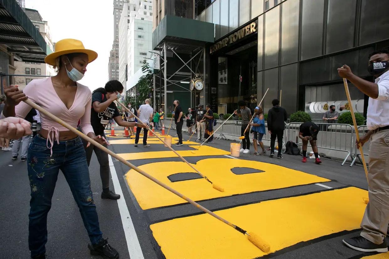 A atriz Azia Toussaint, à esquerda na imagem, participa na pintura do mural "Black Lives Matter" na 5ª Avenida, em frente à Trump Tower, em Nova Iorque.