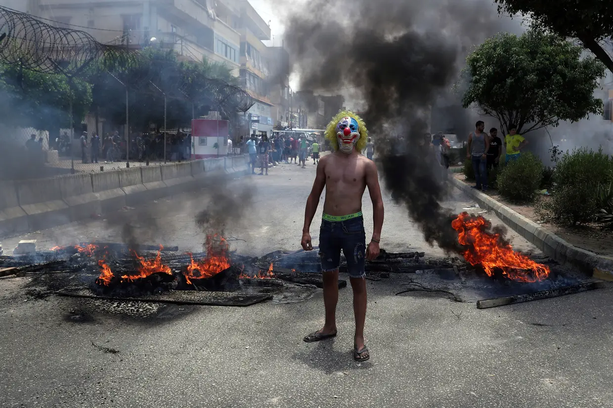 Manifestante antigovernamental entre madeira e pneus queimados para bloquear uma estrada em Beirute, no Líbano.