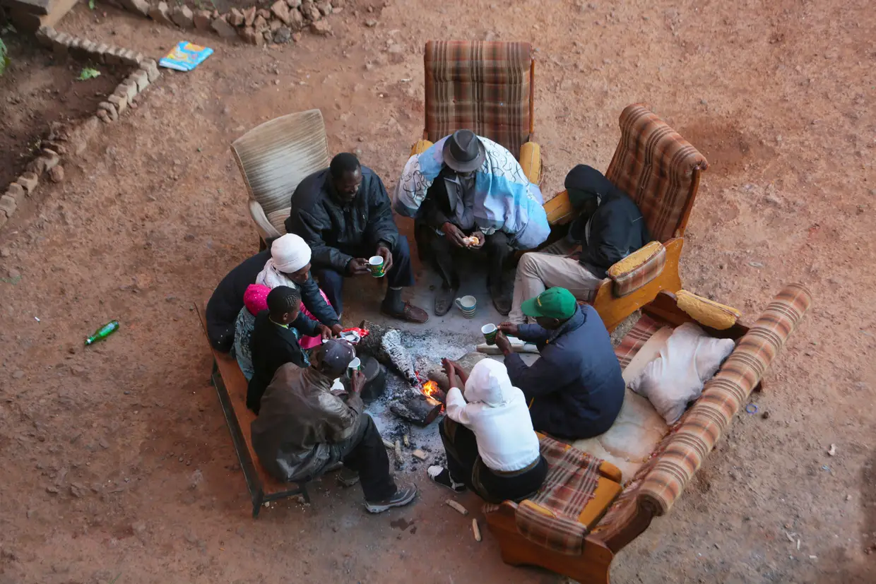 Uma família reunida à volta da fogueira num bairro de Harare, a capital do Zimbabwe.