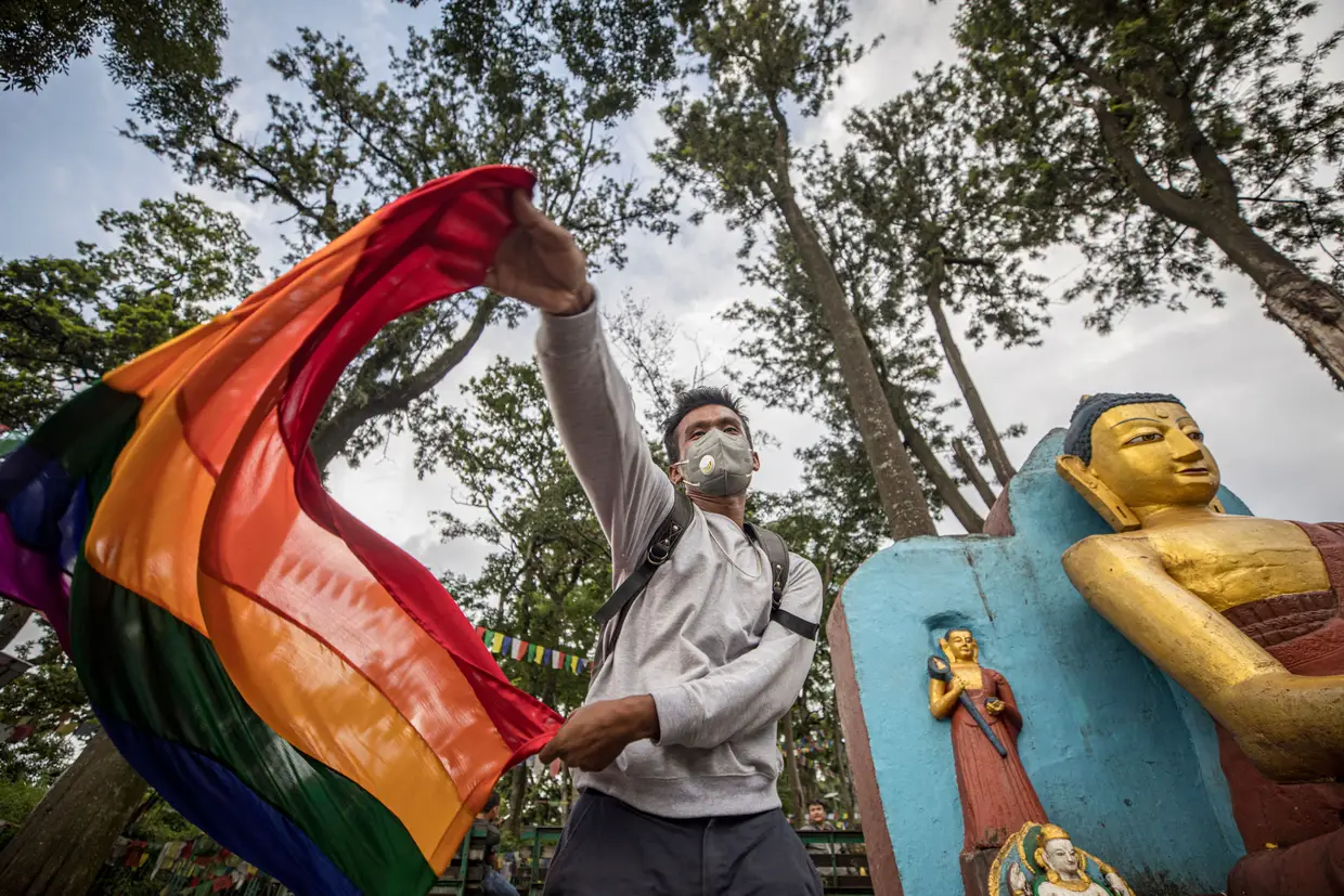 Um transgénero nepalês segura numa bandeira do movimento LGBTQI+ durante uma vigília em homenagem aos membros da comunidade que se suicidaram durante o isolamento.