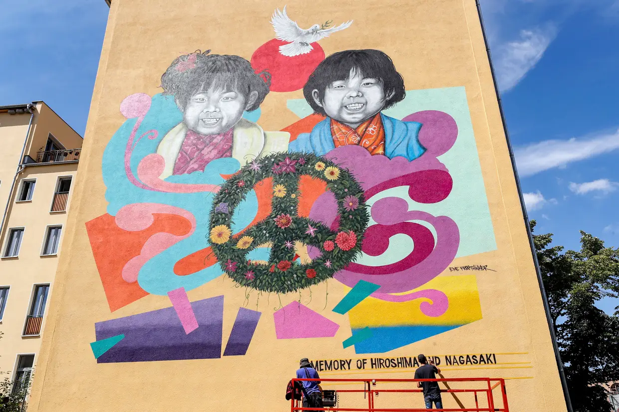 Jesus Cruz Artiles, conhecido como Eme Freethinker, e Francesco Nolli, conhecido por Pen Chill, trabalham num mural para assinalar o 75º aniversário dos bombardeamentos de Hiroshima e Nagasaki, em Berlim, Alemanha.