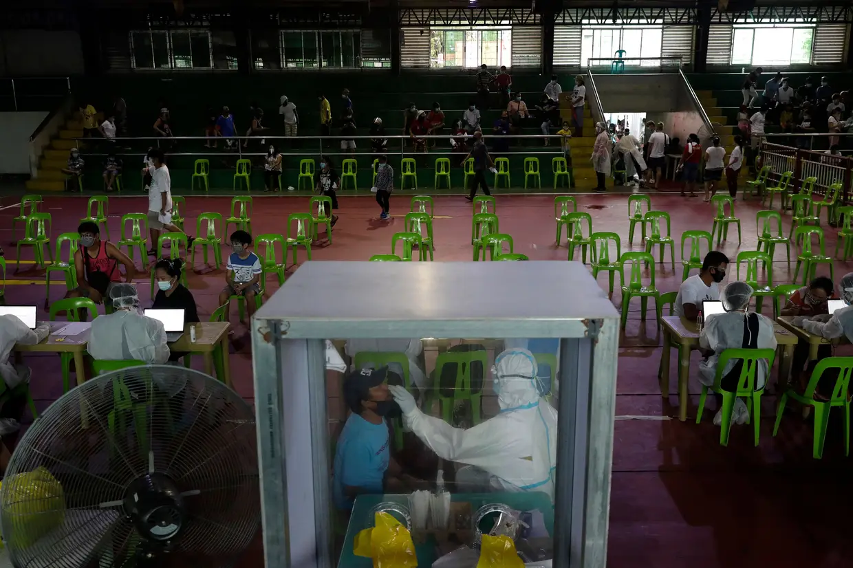 Um profissional de saúde testa um indivíduo para o coronavírus num ginásio transformado em centro de testagem na cidade de Navotas, nas Filipinas.