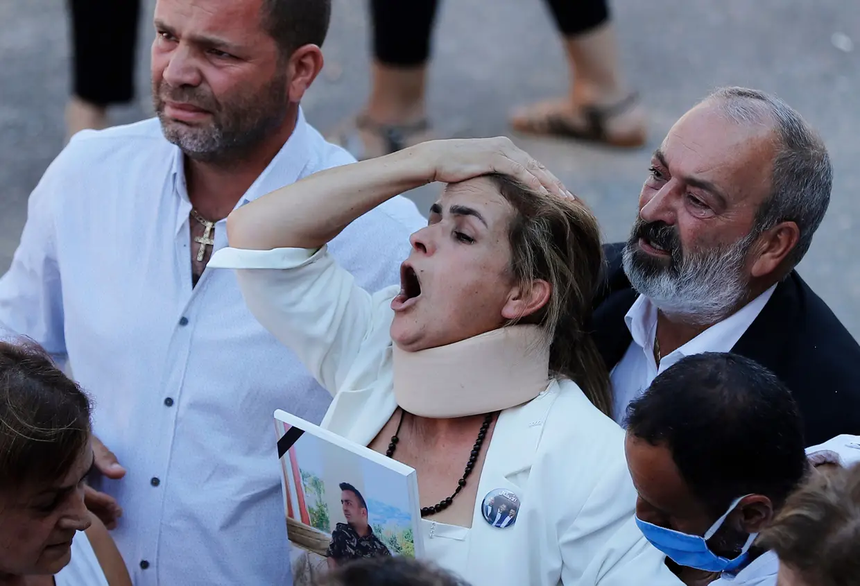A mãe de um dos dez bombeiros que foram mortos durante a explosão no porto de Beirute segura uma fotografia do filho durante o funeral.