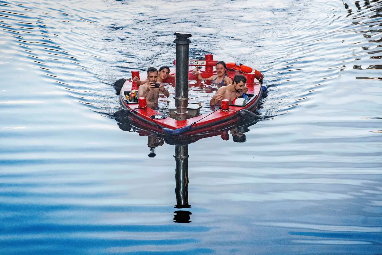 Um grupo de pessoas dentro de um barco em forma de banheira de hidromassagem a navegar no Rio Tamisa, Londres.