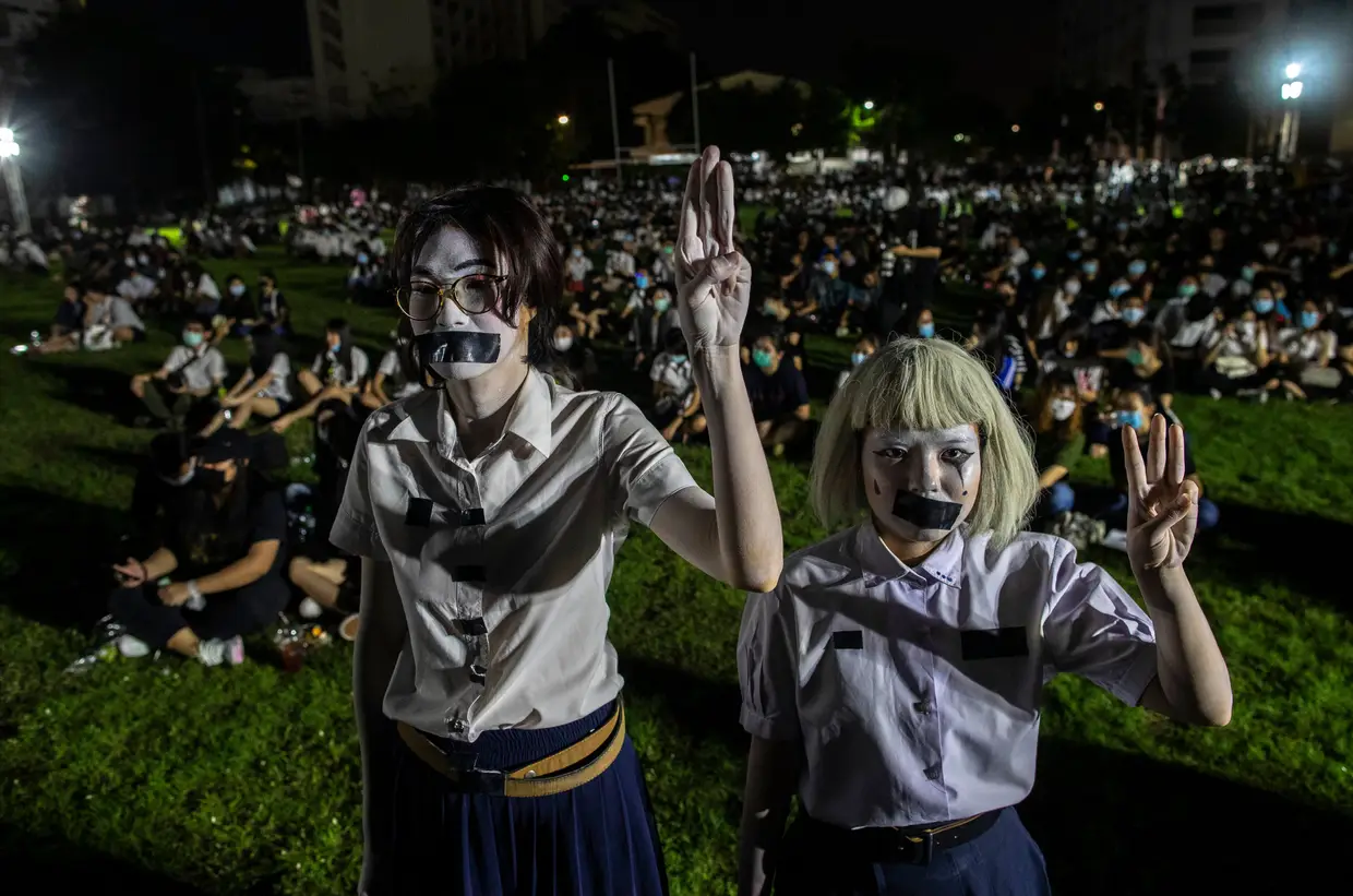 Estudantes pró-democracia com uma fita na boca e três dedos no ar, um símbolo de resistência, durante um protesto na Universidade de Mahidol, na Tailândia. Estes alunos pedem novas eleições, revisão da constituição e o fim da intimidação aos críticos do Governo.