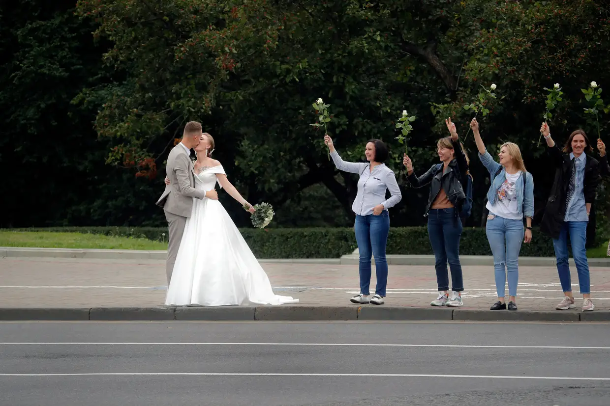 Recém-casados beijam-se enquanto apoiantes da oposição bielorrussa manifestam-se, Minsk.
