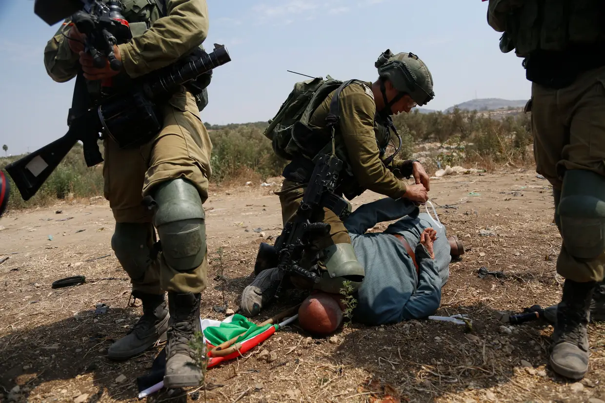 Soldados israelistas detém um palestino durante um protesto contra a expansão na aldeia de Shufa, na Cisjordânia