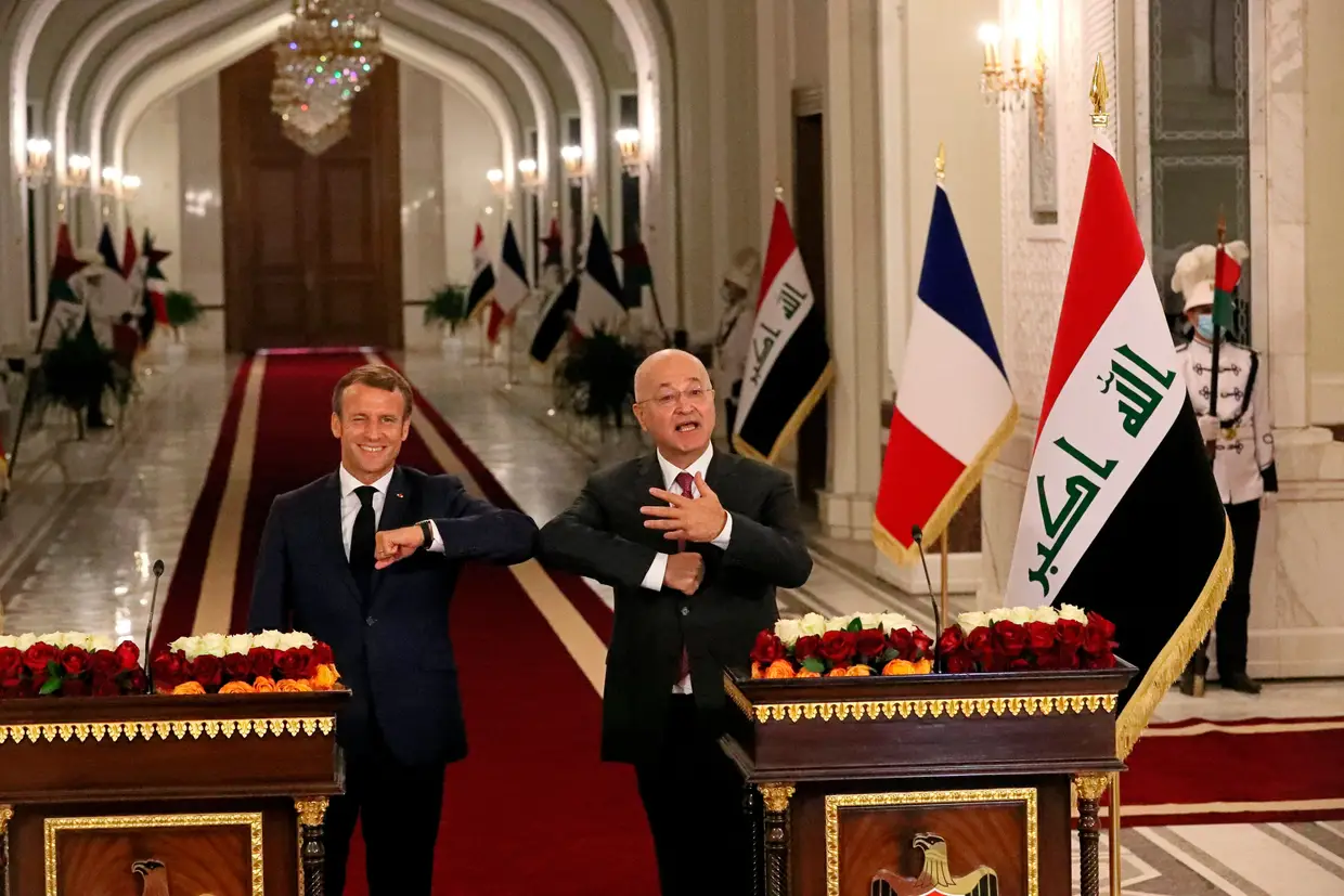 O Presidente francês, Emmanuel Macron (E), cumprimenta com o cotovelo o Presidente iraquiano, Barham Salihat (D), durante uma conferência de imprensa no Palácio Presidencial em Bagdade.