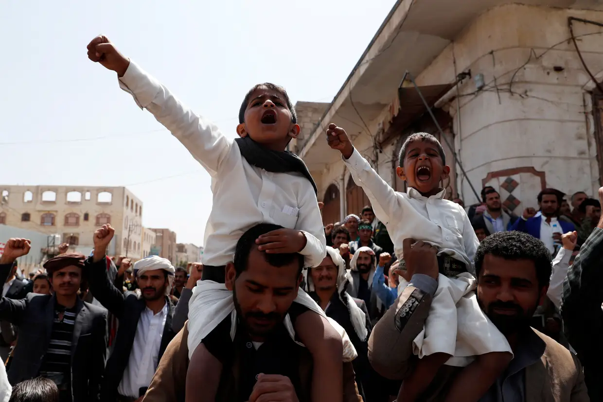 Dois xiitas do Iémen pró-Huthi carregam duas crianças que gritam "slogans" contra a coligação da Arábia Saudita e Emirados Árabes Unidos.