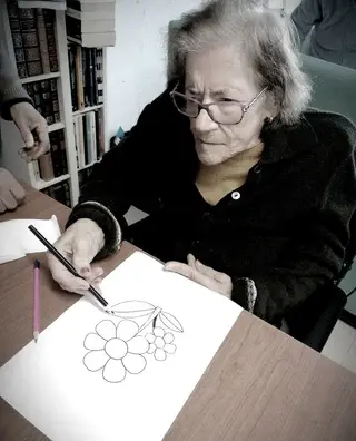 Maria do Céu a pintar um desenho no lar.