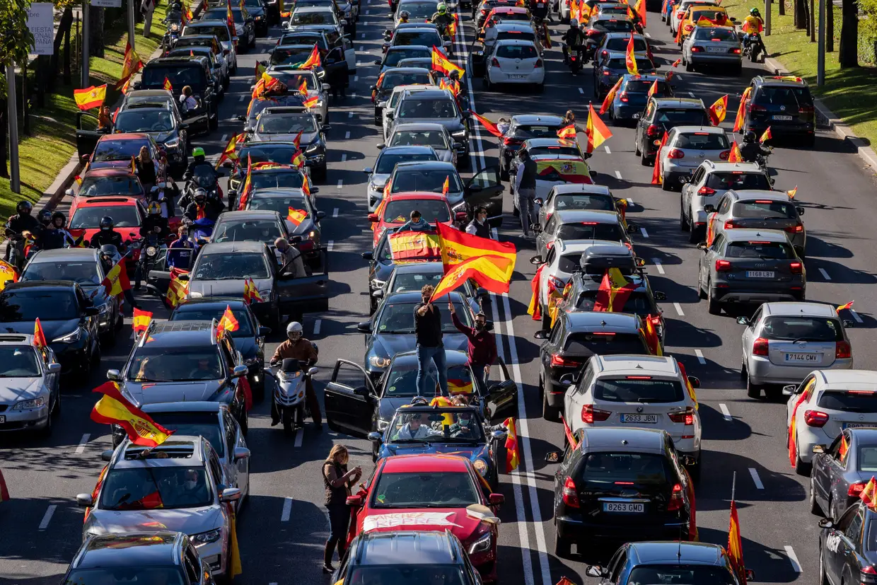 Cidadãos descontentes abanam a bandeira de Espanha num protesto, organizado pelo partido de extrema-direita, Vox. contra as medidas anunciadas pelo governo para conter a propagação da pandemia em Madrid,