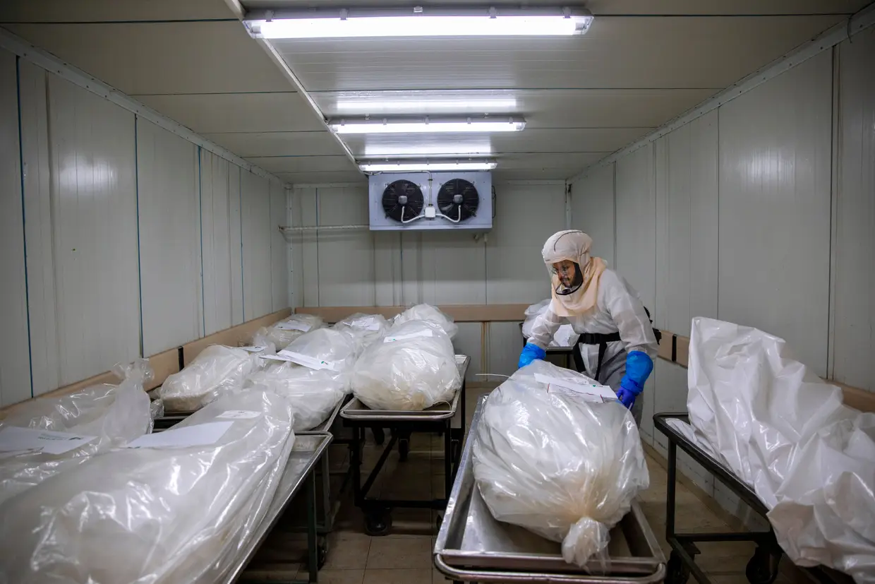 Um trabalhador da sociedade funerária judaica de Israel prepara os corpos antes de um cortejo fúnebre numa morgue especial para as vítimas da Covid-19.