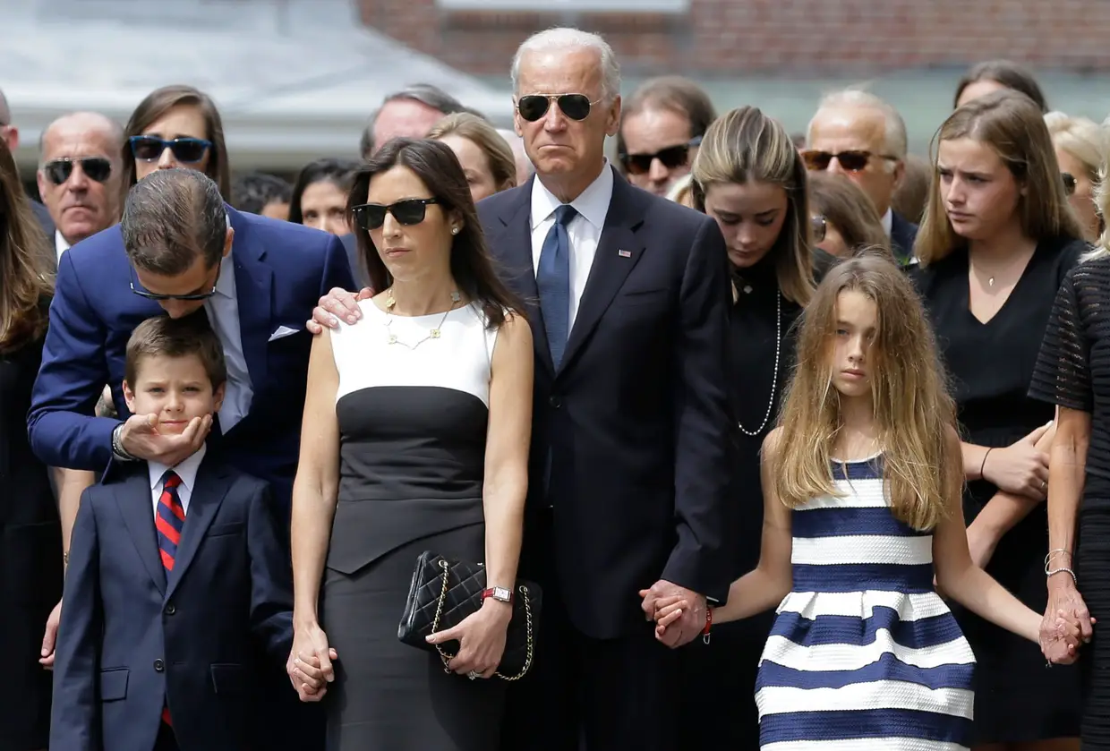 Funeral de Beau Biden, filho de Joe, 6 de junho de 2015. Hunter Biden (esquerda), irmão de Beau, beija o sobrinho. Ao seu lado lado estão a viúva de Beau, Hallie, Joe Biden, o pai, e Natalie, filha do falecido.