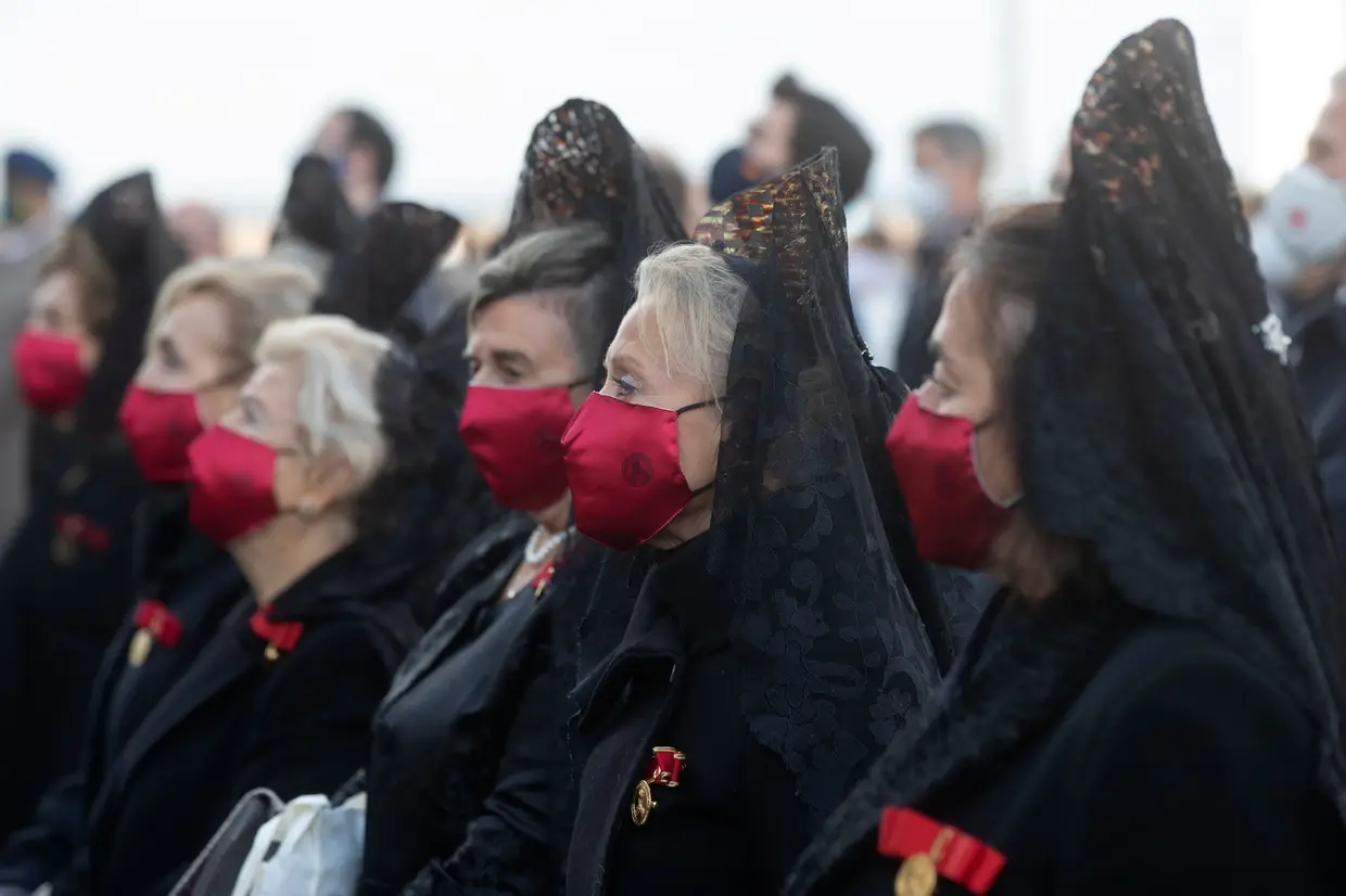 Mulheres vestidas com trajes tradicionais e a usar máscaras para se protegerem, participam numa missa ao ar livre para celebrar a virgem da santa padroeira de Madrid, La Almudena, em Madrid, Espanha.