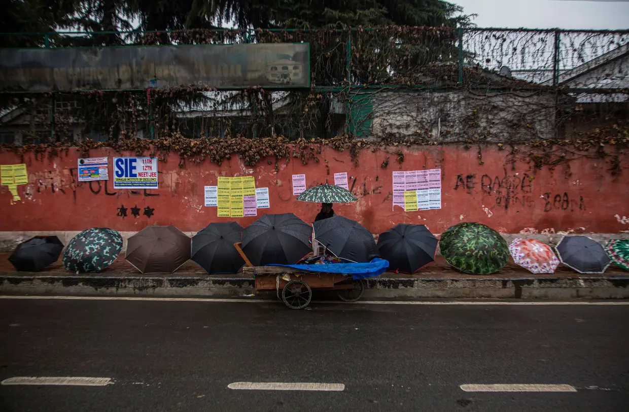 Um vendedor de rua vende chapéus de chuva em Srinagar, Caxemira