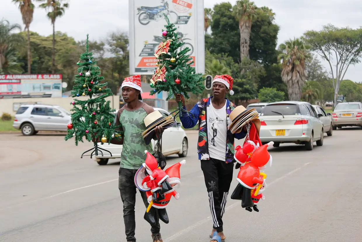 Dois homens vendem árvores de natal e pais natais no trânsito em Harare, no Zimbabué.