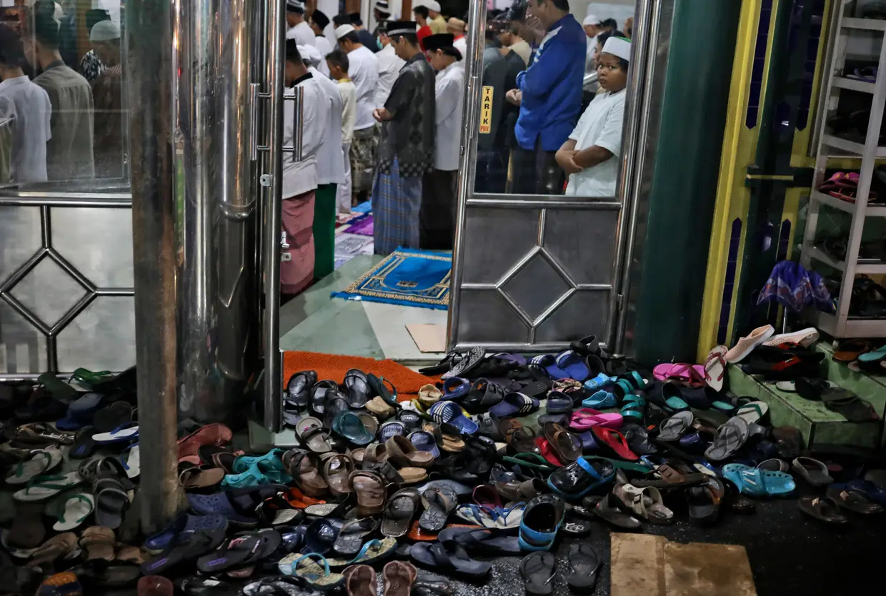 Os sapatos são deixados à porta, enquanto se realiza a reza "tarawih" durante a primeira noite do mês do Ramadão, em Jacarta, na Indonésia.