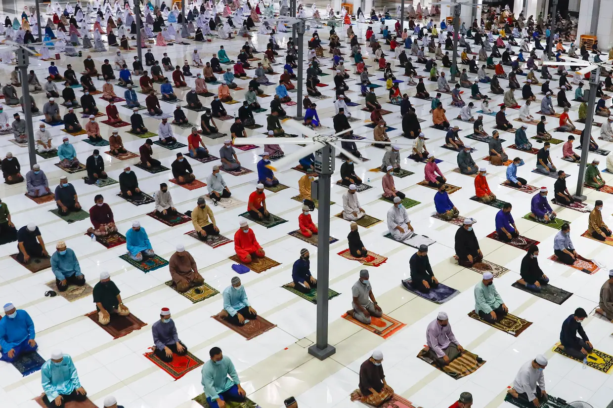 Muçulmanos malaios mantêm distância social e usam máscara de proteção enquanto participam nas celebrações da véspera do Ramadão, em Putrajaya, na Malásia.