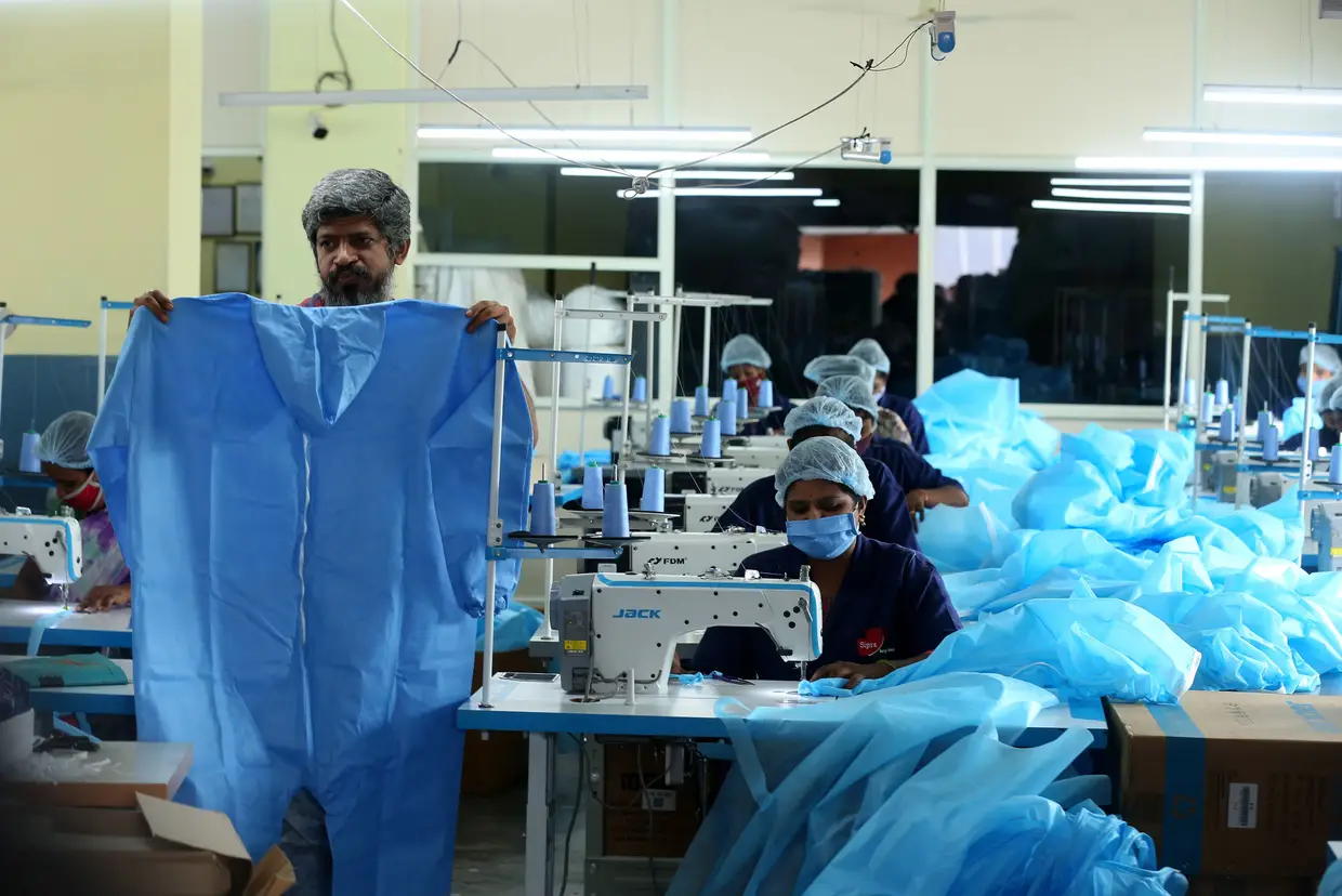 Trabalhadores indianos produzem kits de proteção individual numa fábrica em Bangalore.