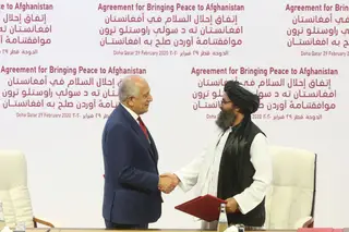 O enviado de paz dos EUA, Zalmay Khalilzad, à esquerda, e o Mullah Abdul Ghani Baradar, o principal líder político dos talibãs, cumprimentam-se depois de assinar um acordo de paz em Doha, no Qatar, em fevereiro de 2020.