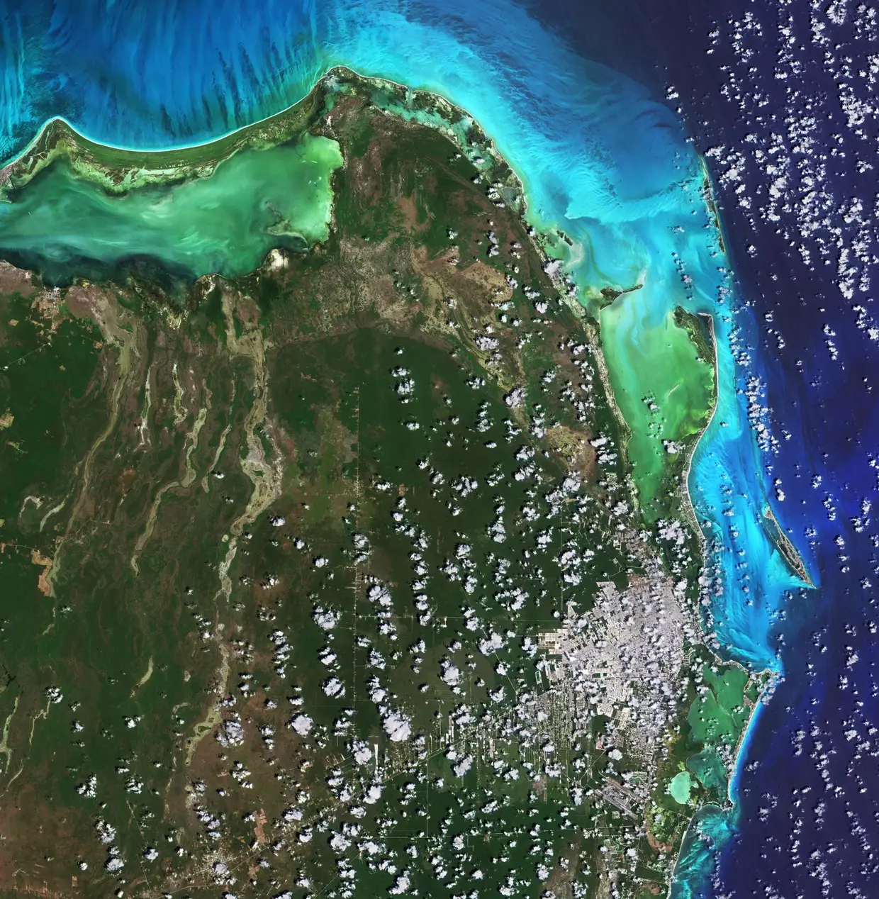 Cancún, na Península do Iucatão no México, junto ao mar das Caraíbas. O clima tropical e as praias fizeram da cidade e da Riviera Maia, ao sul de Cancún, um dos principais destinos turísticos do México. Nesta imagem, capturada em 16 de abril de 2021, a cidade pode ser vista no canto inferior direito, envolta em nuvens. O Aeroporto Internacional de Cancún, o segundo aeroporto mais movimentado do México, está localizado a cerca de 20 km ao sul da cidade.
