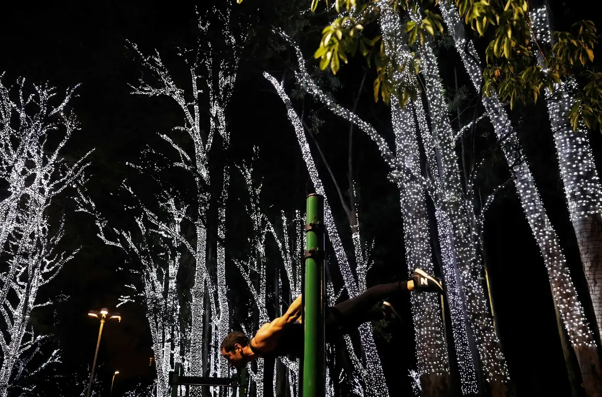 Um homem faz exercício no Parque Ibirapuera, em São Paulo, junto de árvores iluminadas na cidade brasileira