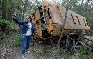 Turista tira uma selfie junto a um autocarro abandonado durante uma tour em Chernobyl (Ucrânia, 7 de junho de 2019)