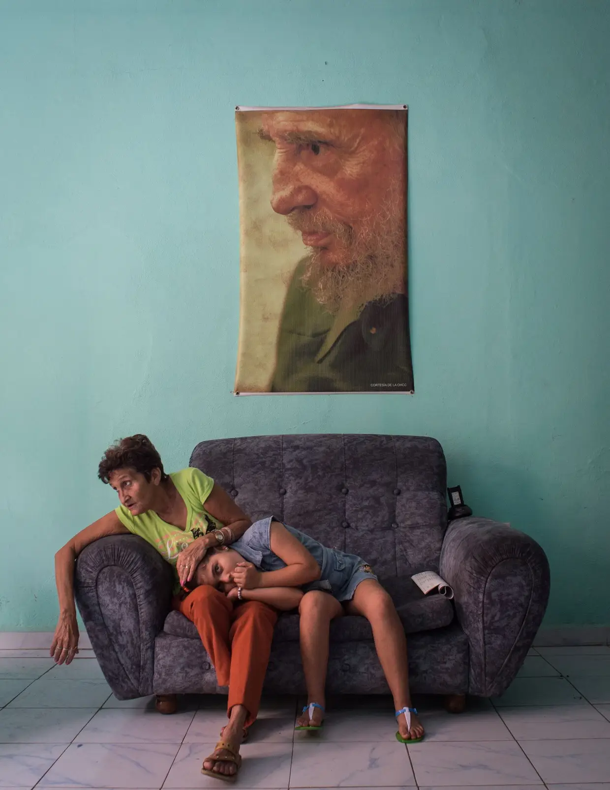 Terceiro lugar na categoria de PEssoas, da autoria de Kristina Kormilitsyna, da Rússia. Mãe e filha cubanas, num sofá, sob a imagem de Fidel Castro.