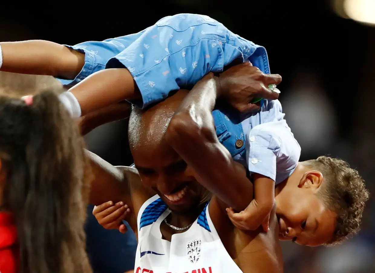 O britânico Mo Forah celebra com o filho o seu terceiro título mundial nos 10.000 metros