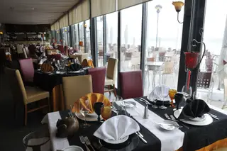A sala e bar envidraçados, amplos, cheios de luz natural, estão separados apenas por um piano de cauda, e a varanda protegida do vento, mas aberta à brisa e à maresia