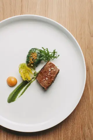 O cordeiro de leite assado, funcho glaceado, barriga com crosta de alho fresco e farinha de mandioca e cevadinha com os miúdos