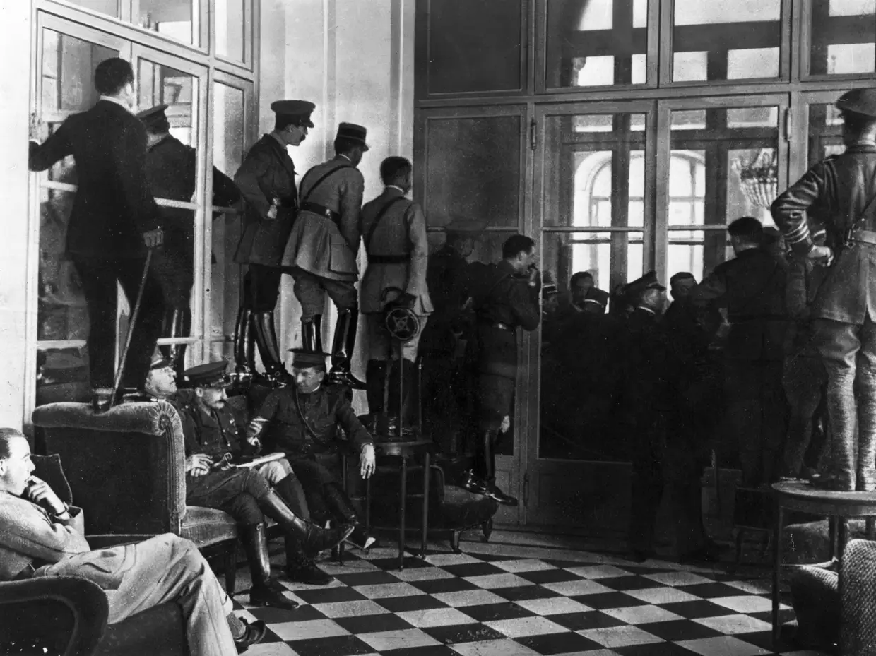1918 - Soldados procuram o melhor ângulo para espreitar para dentro da Sala dos Espelhos onde o Tratado de Paz de Versalhes está a ser assinado