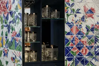 O interior, revestido a veludo azul, guarda o serviço de copos de cristal