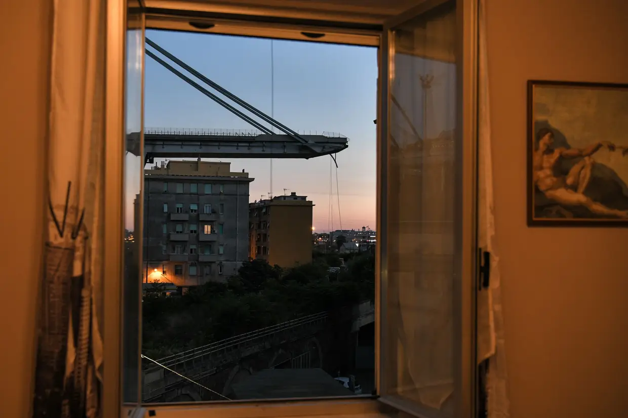 Uma visão geral feita através de uma janela mostra prédios de apartamentos sob a ponte da auto-estrada Morandi um dia depois que uma seção desabou em Gênova em 15 de agosto de 2018