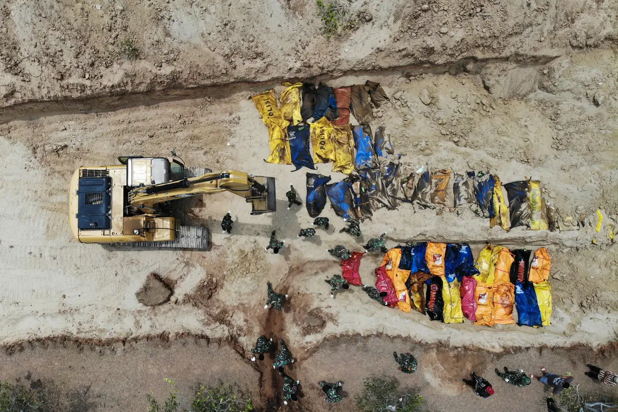 Esta foto aérea mostra soldados indonésios enterrando vítimas do terremoto numa vala comum em Poboya, no Sulawesi Central da Indonésia, em 2 de outubro de 2018, depois que um terremoto e um tsunami atingiram a área em 28 de setembro
