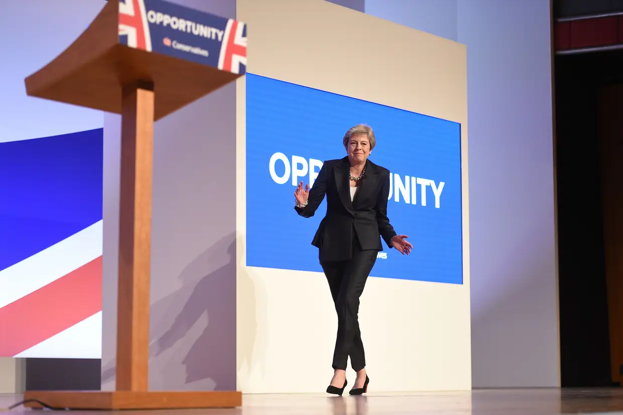 A primeira-ministra britânica, Theresa May, dança alguns passos enquanto sobe ao palco para discursar no quarto e último dia da Conferência do Partido Conservador de 2018 no International Convention Center, em Birmingham, no centro da Inglaterra, em 3 de outubro de 2018