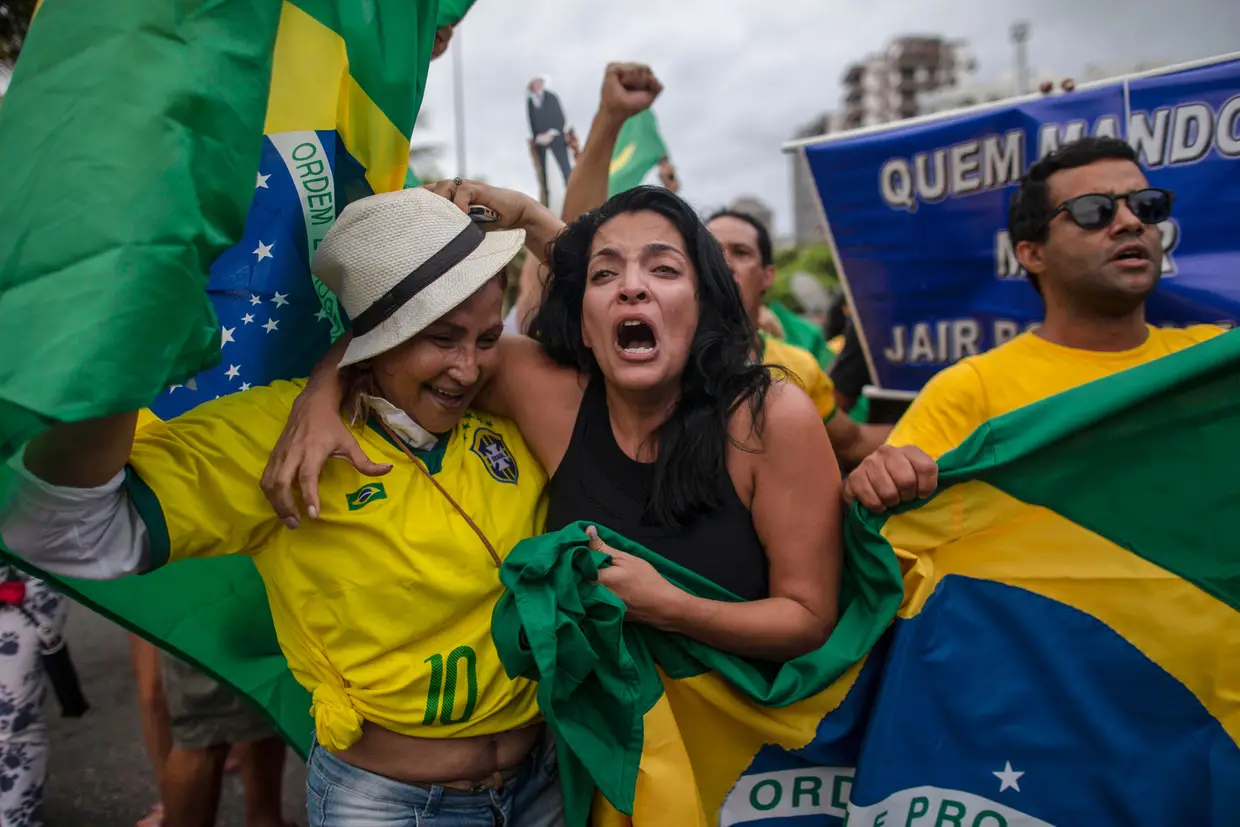 Apoiantes do candidato presidencial brasileiro pelo Partido Social Liberal, Jair Bolsonaro aplaudem em frente ao condomínio residencial onde ele mora, na Barra da Tijuca, no Rio de Janeiro, Brasil, em 7 de outubro de 2018, durante as eleições gerais