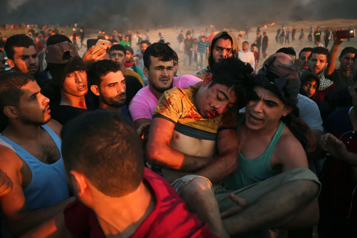Manifestantes palestinianos carregam um jovem ferido durante confrontos com forças israelitas na fronteira entre Israel e Gaza, a leste da cidade de Gaza, em 12 de outubro de 2018. Cinco palestinos foram mortos em novos confrontos