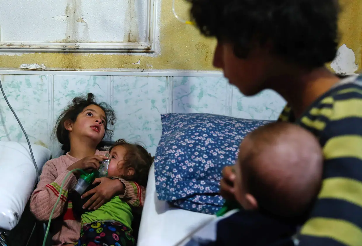 Nenina síria segura uma máscara de oxigênio sobre o rosto de uma criança num hospital improvisado após um ataque a gás na cidade sitiada de Douma, na região de Ghouta, nos arredores da capital Damasco, em 22 de janeiro de 2018