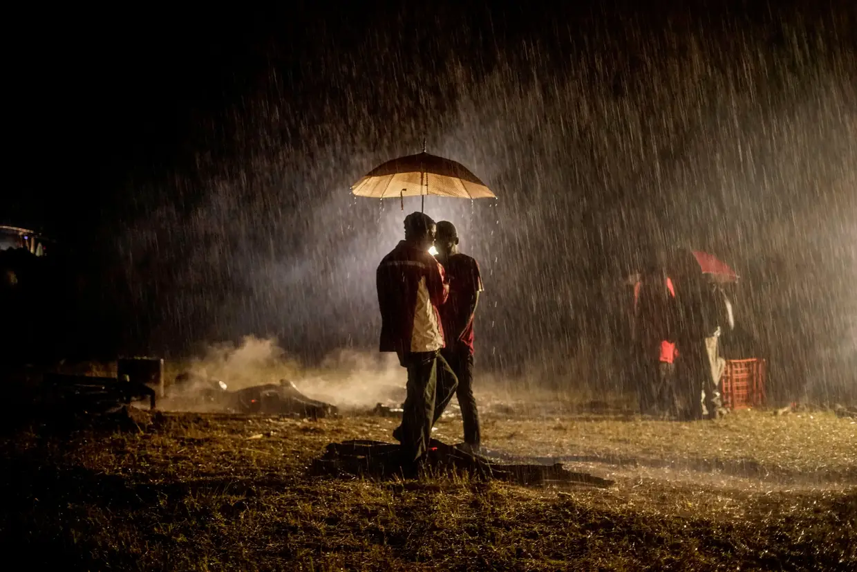 Os apoiantes do falecido líder da oposição do Zimbabué, Morgan Tsvangirai, reúnem-se sob um guarda-chuva durante uma tempestade de chuvas antes do seu enterro na aldeia de Humanikwa, Buhera, em 20 de fevereiro de 2018
