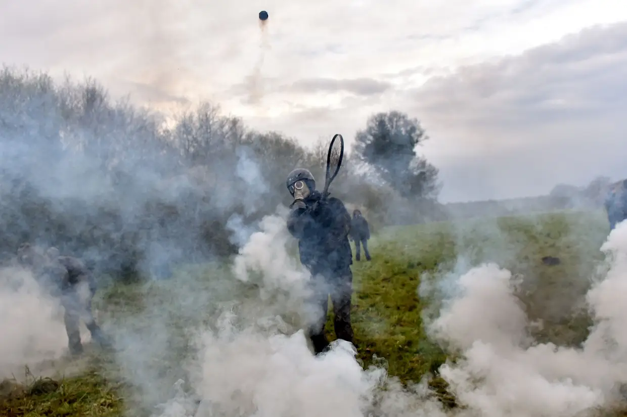 Um manifestante usa uma raquete de ténis para lançar uma bomba de gás lacrimogénio contra as tropas de choque quando surgem choques durante uma operação policial para demolir um campo conhecido durante décadas como ZAD (Zona a Defender) em Notre-Dame-des-Landes, perto de a cidade de Nantes, no oeste do país, em 10 de abril de 2018, e despejar o último dos manifestantes que se recusaram a sair. A polícia francesa lutou para expulsar os manifestantes anti-aeroporto e os criadores de um assentamento anticapitalista alternativo no oeste da França durante um segundo dia de confrontos. Cerca de 2.500 policias invadiram o campo, destruindo casas improvisados, um barracão gigante, uma torre de vigia, um curral de ovelhas e uma área de produção de queijos.