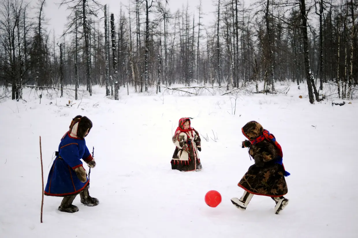 Crianças de pastores de rena jogam com uma bola na neve na região de Yamalo-Nenets remota de Rússia do norte