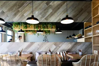 Na decoração, com mesas e madeiras de cor natural, destacam-se as almofadas de cores sóbrias e muitas plantas